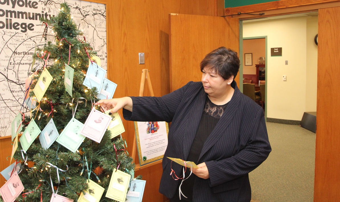 HCC president Christina Royal picks some gift tags off the HCC Giving Tree.