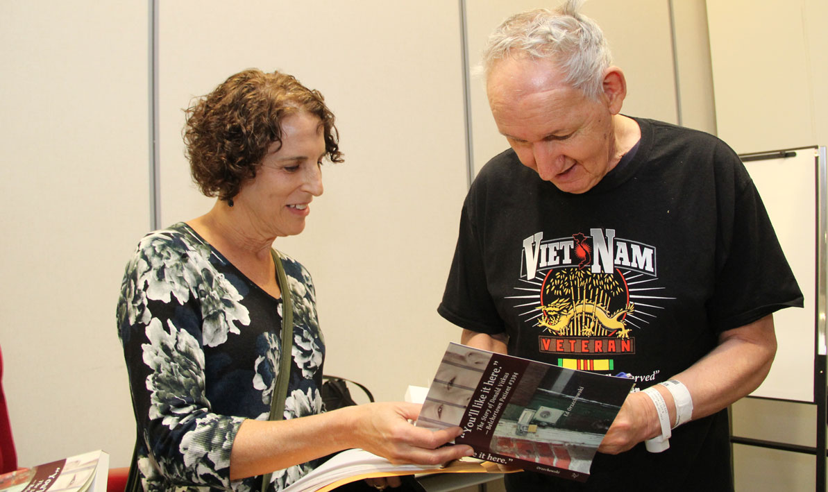 HCC alum Donald Vitkus, '05, signs a copy of 'You'll Like It Here,' the story of his life, for HCC teacher Janet Grant. 