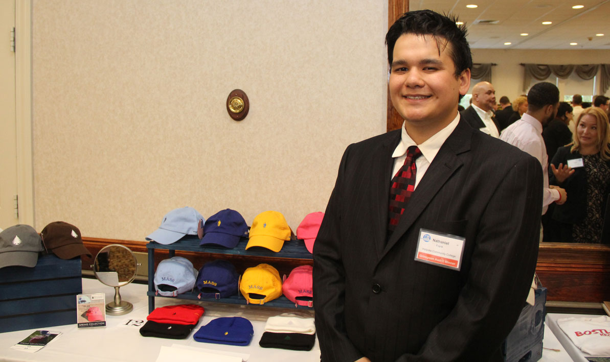 HCC student Nate Frank stands next to an assortment of hats from his business Bay State Brimmers. 
