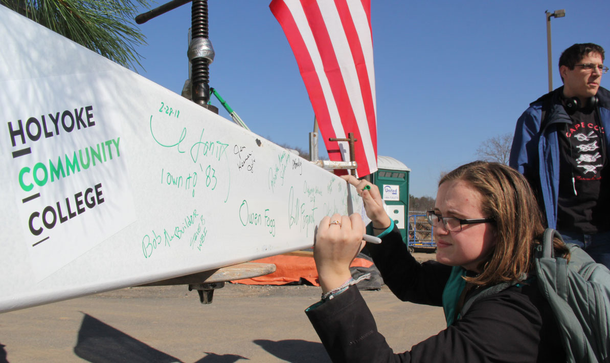 Student signs name to ceremonial beam