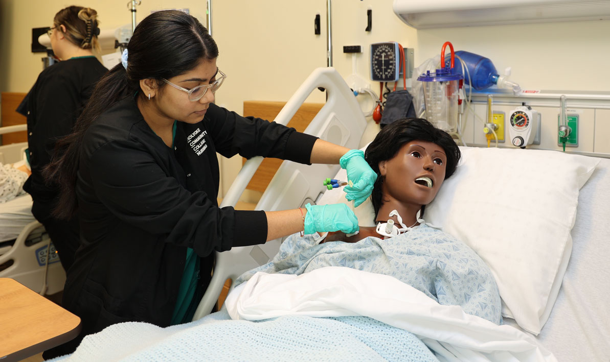 A student checks on a patient in an HCC simulation lab