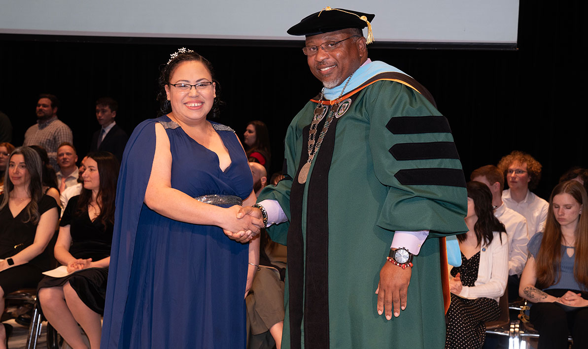 Maryagnelly Varas-Gonzalez shakes hands with President George Timmons. 
