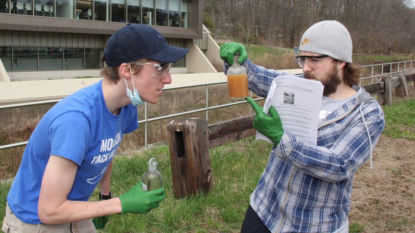 Two environmental science students examine a beaker