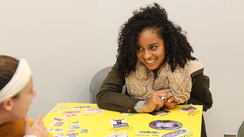 An education student smiles as they create a posterboard display