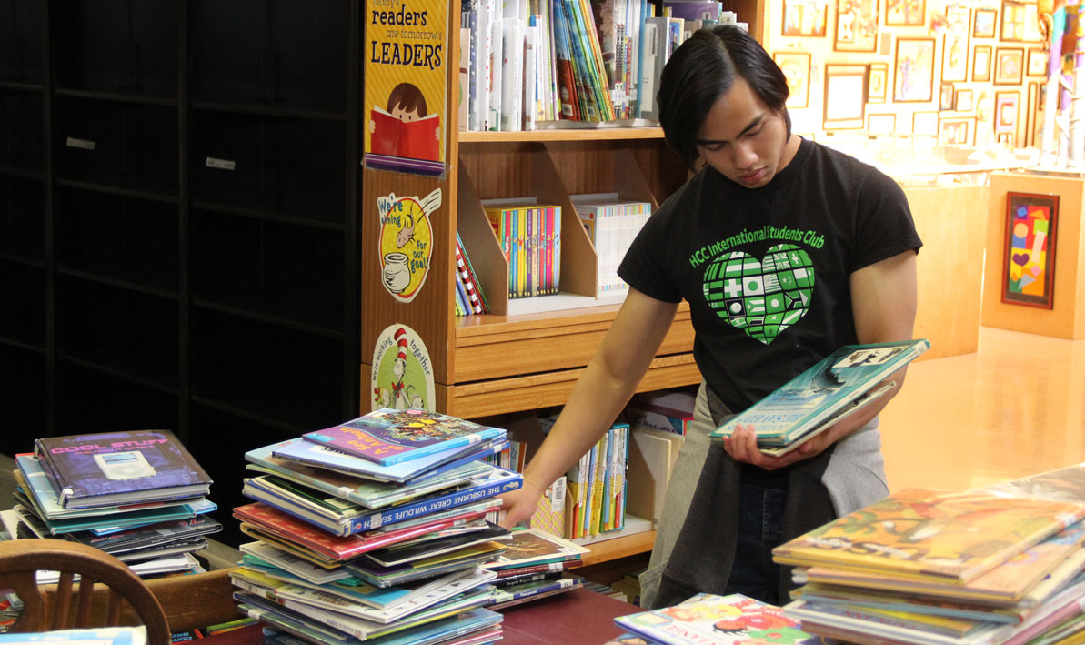 HCC student Siman Kamarudin, '17, sorts books in the library at Kelly Elementary School in Holyoke. 