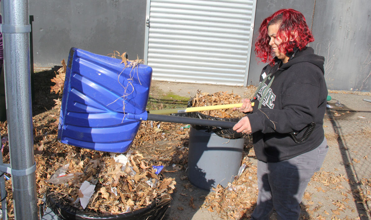 HCC student Frances Rivera Diaz picks up trash and leaves outside the Kelly Elementary School in Holyoke.