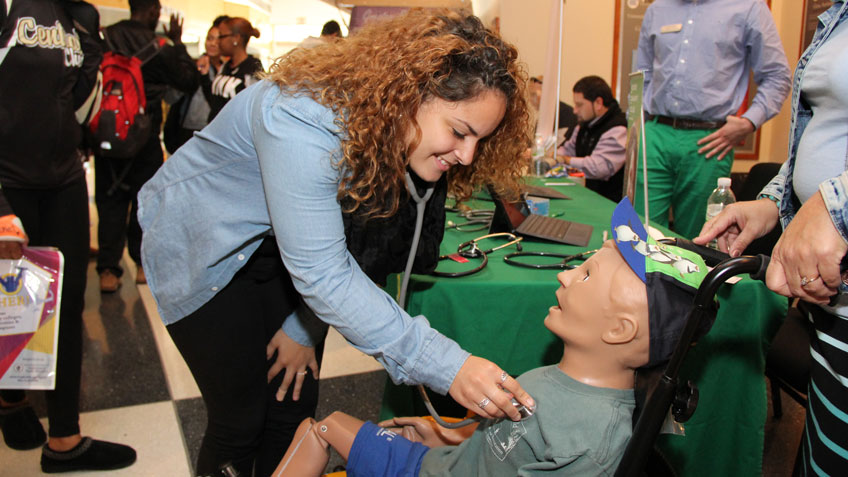 Kassandra Rivera, 18, a senior at Springfield  Central High School, listens to the heartbeat of a patient simulator from HCC at a Go Higher college fair this week at the Basketball Hall of Fame.