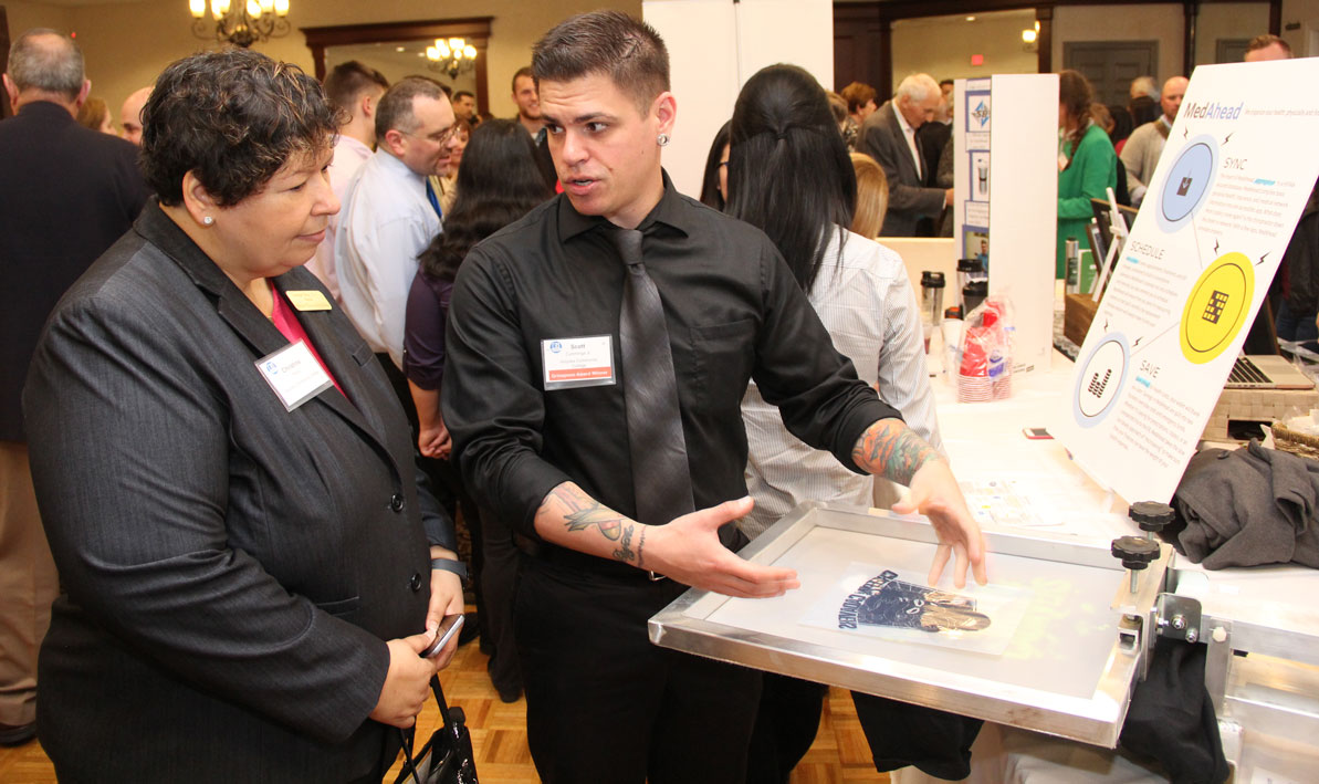 HCC student Scott Cummings explains the silk-screening process to HCC president Christina Royal. 