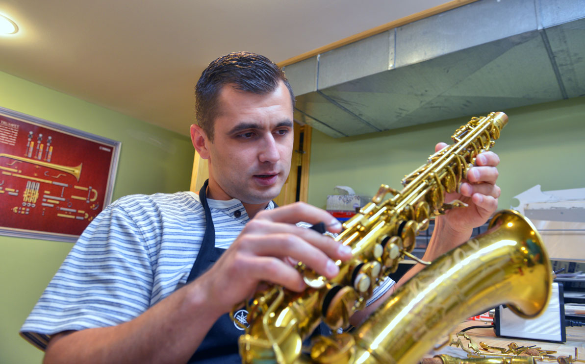 Roman repairs a saxaphone in the Dubchaks' basement workshop. 