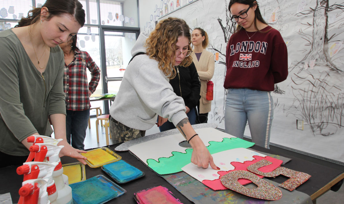 HCC students put their thumbprints on a birthday cake card they made for Eric Carle Museum's 50th anniversary celebration for the Very Hungry Caterpillar. 