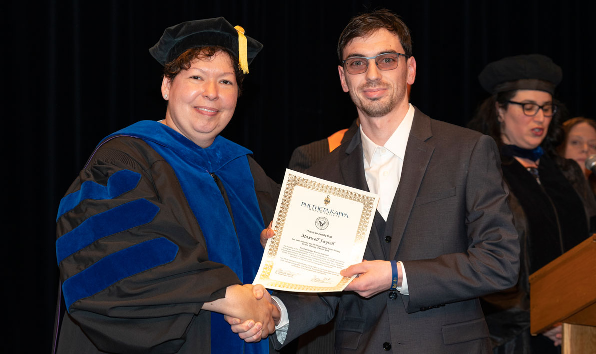 President Christina Royal congratulates HCC student Maxwll Faytell on his induction into the college chapter of the PHi Theta Kappa national honor society.