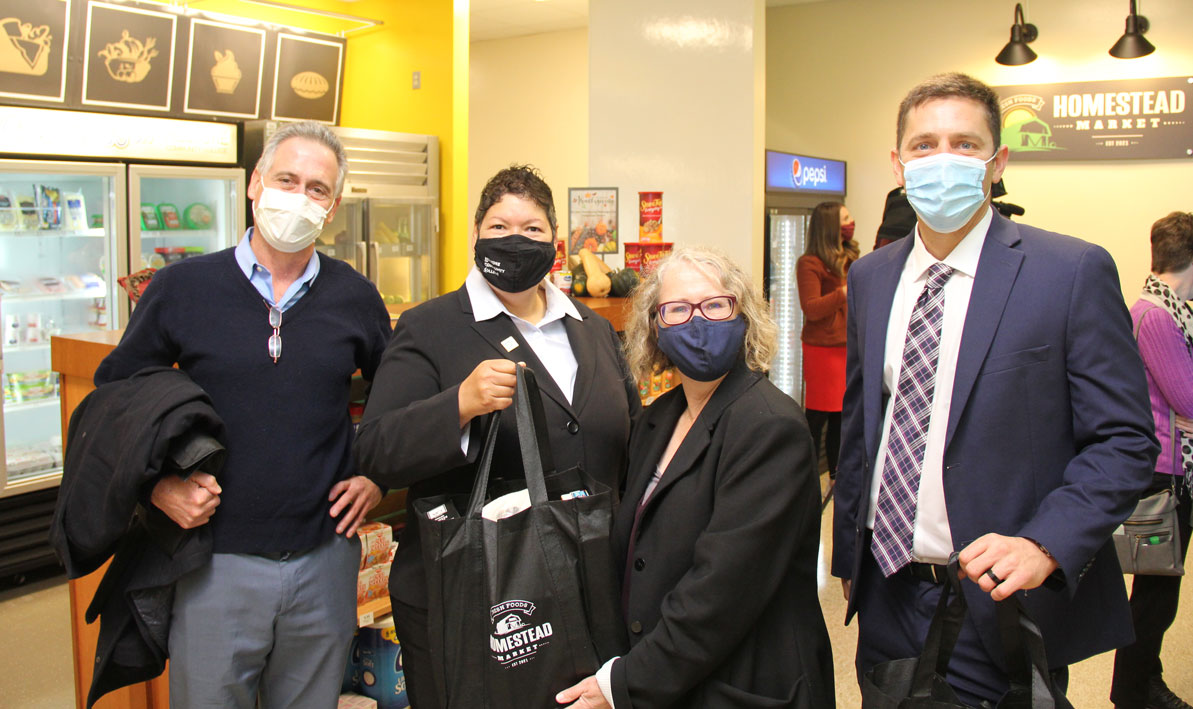 President Royal and others hold a bag full of groceries from Homestead Market