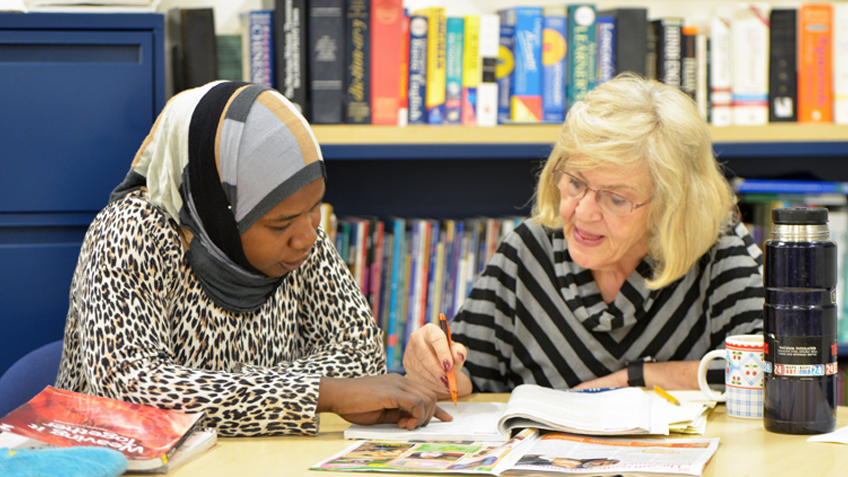 Staff person helping student at desk