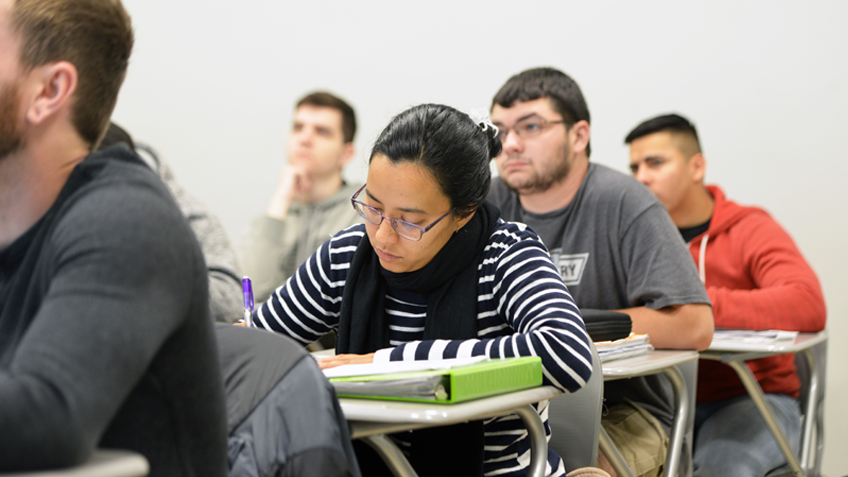 A student writes in a notebook in class