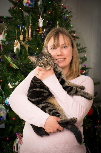 Erin Jackson stands in front of a Christmas tree holding a cat in her arms