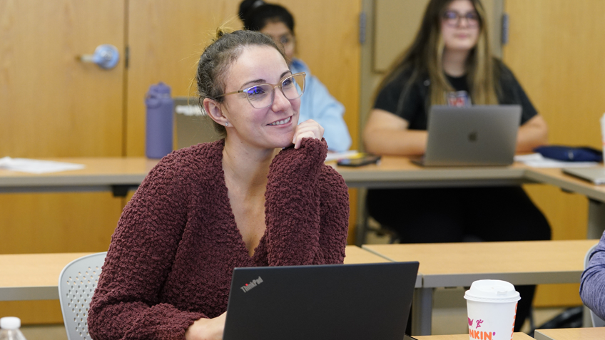 A student sitting in a classroom smiles