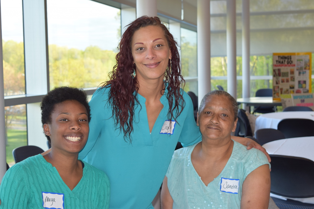 A group of three women smiling and wearing nametags