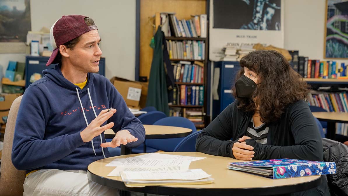 A student and advisor sit at a table together.