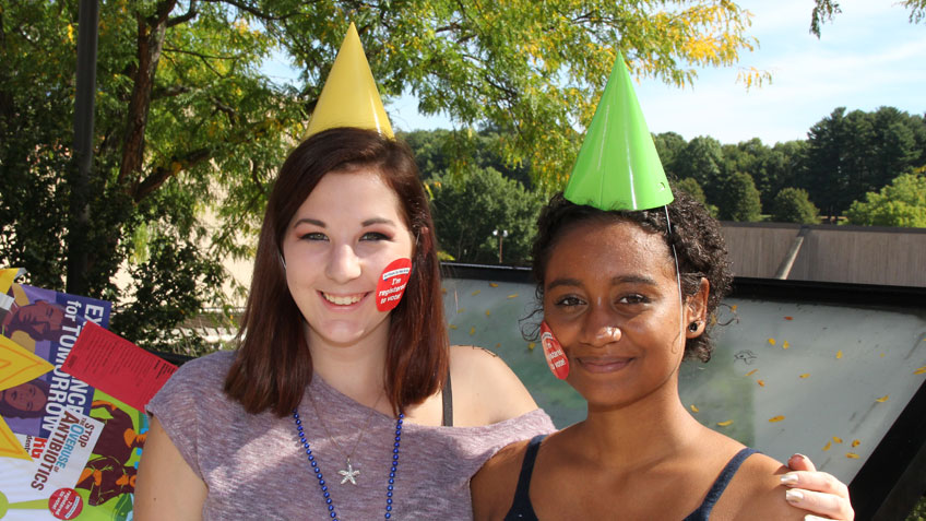 Two smiling students wearing party hats